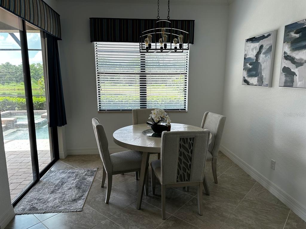 A dining area features a round table, four chairs, a chandelier, and a sliding glass door — 17025 POLO TRAIL, BRADENTON, FL