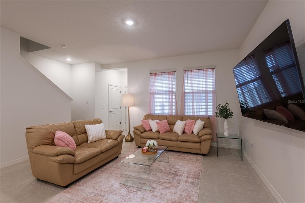 A living room features two tan leather sofas, a glass coffee table, and a television — 10807 E FORT WHITE COURT, TAMPA, FL