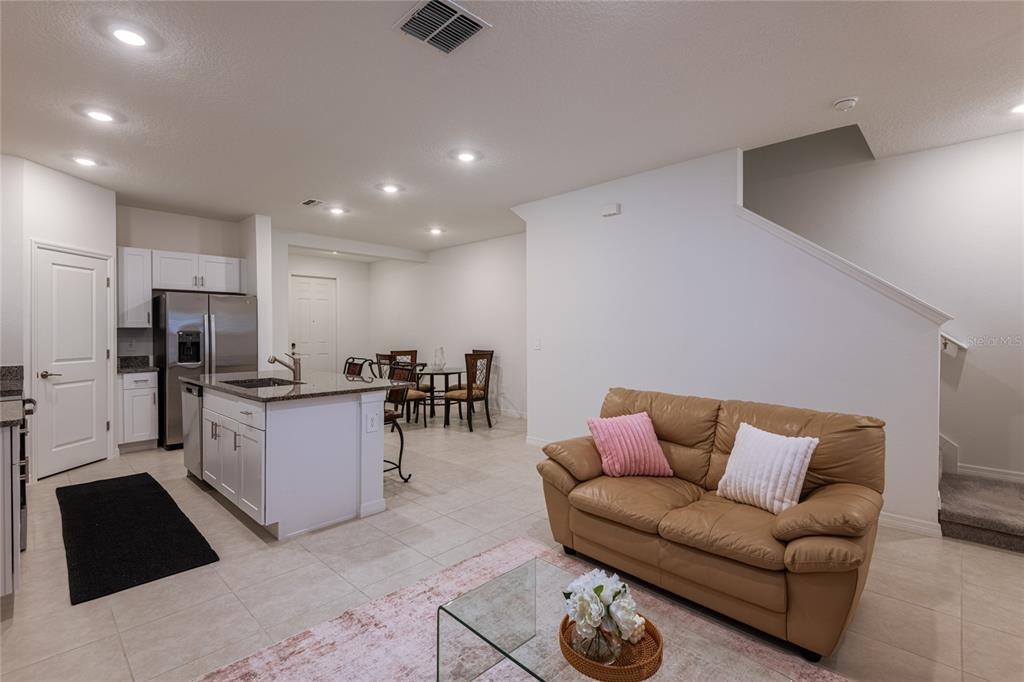 An open-concept kitchen and living area features white cabinets, a kitchen island, and a sofa — 10807 E FORT WHITE COURT, TAMPA, FL