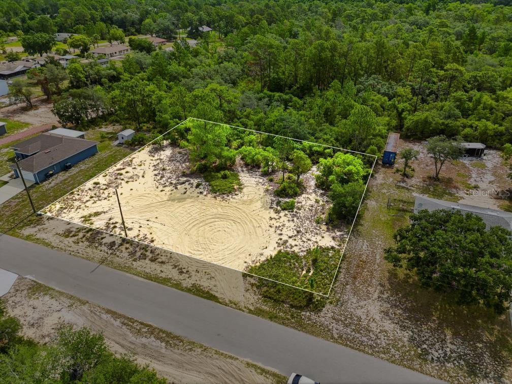 An aerial view shows a vacant, sandy residential lot outlined in white near a road — LEMON DRIVE, LAKE WALES, FL