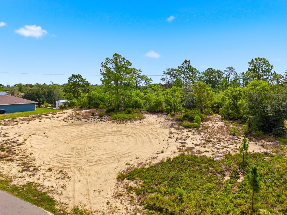 An elevated view of a sandy, cleared residential lot surrounded by trees and nearby houses — LEMON DRIVE, LAKE WALES, FL
