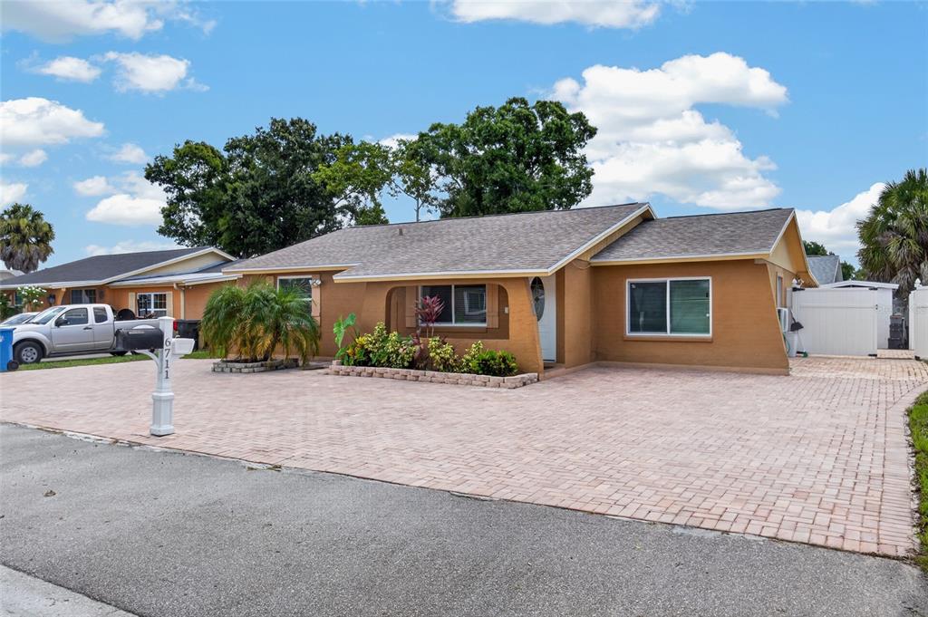 A tan single-story house with a paved driveway and a small front garden — 6711 GLEN FOREST COURT, TAMPA, FL