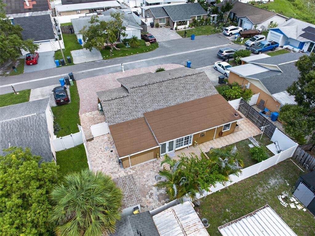 An aerial view shows a house with a brown roof, paved patio, and fenced backyard — 6711 GLEN FOREST COURT, TAMPA, FL