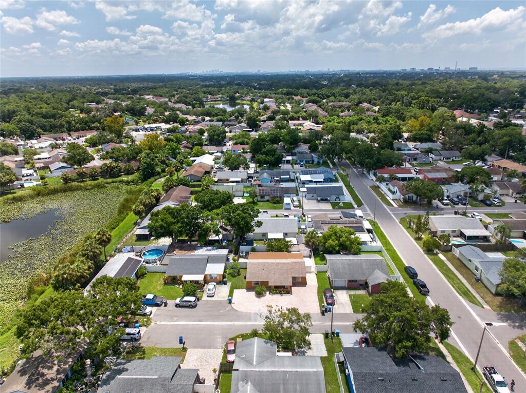 An aerial view shows a suburban neighborhood with houses, streets, and a pond — 6711 GLEN FOREST COURT, TAMPA, FL