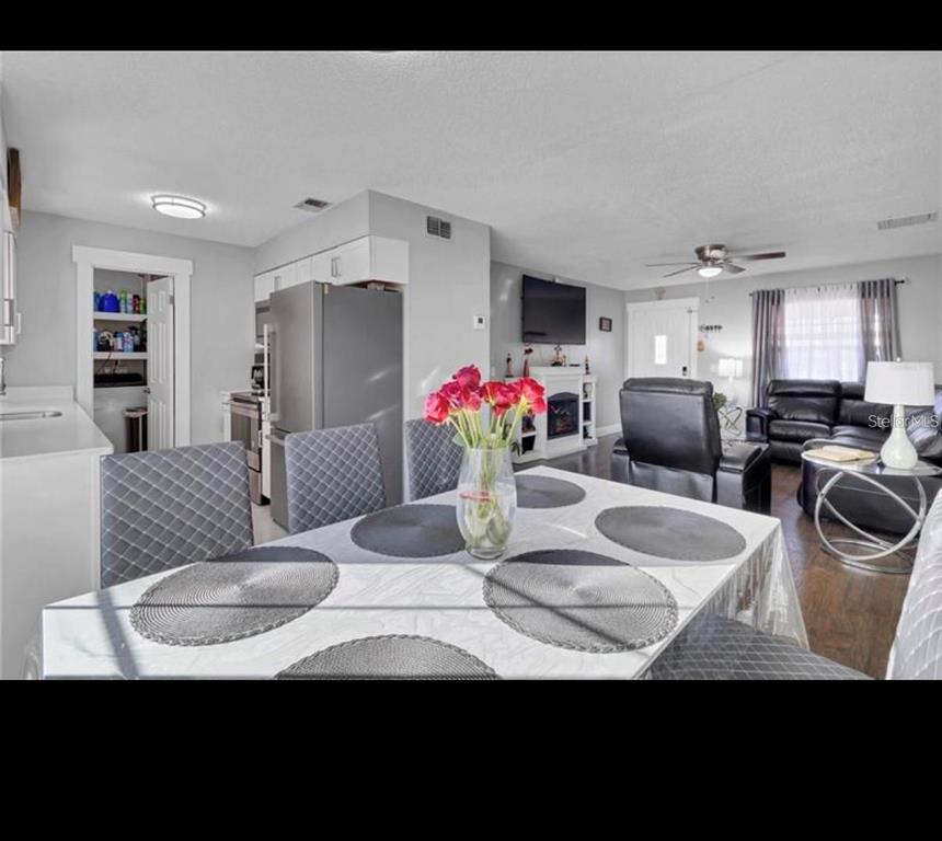 A dining area with a table and chairs opens into a living room with a fireplace — 314 W GROSSENBACHER DRIVE, APOPKA, FL