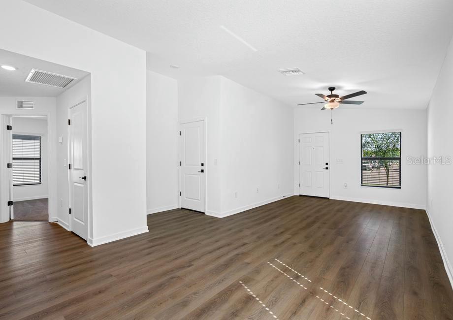 A bright living room features white walls, wood-look flooring, a ceiling fan, and a front door — 657 BLACKTHORN DRIVE, LAKELAND, FL