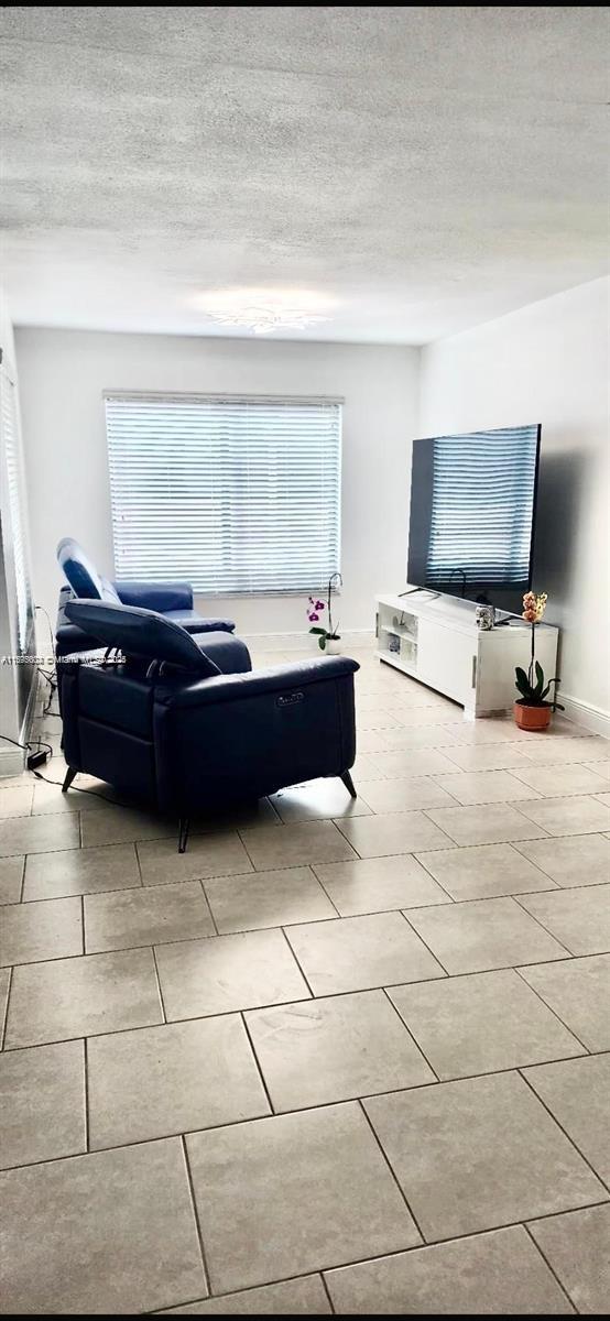 A living room features light tile flooring, a blue recliner, and a television on a console — 13208 SW 10th Ln, Miami FL 33184, MIAMI, FL