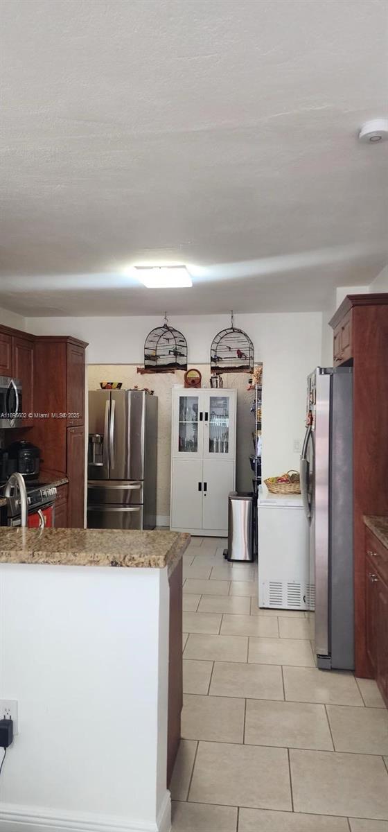 A kitchen features wood cabinets, stainless steel appliances, tile flooring, and two hanging birdcages — 13208 SW 10th Ln, Miami FL 33184, MIAMI, FL
