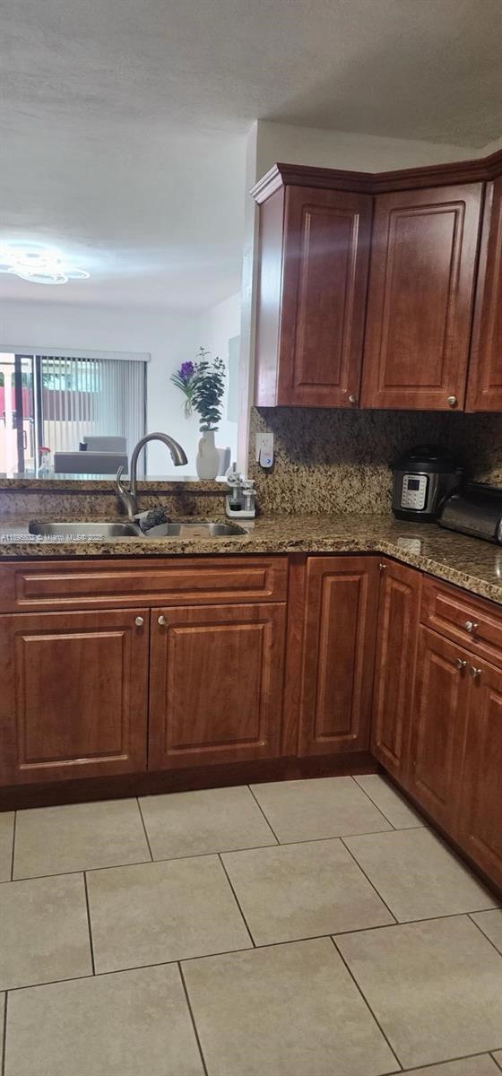 A kitchen features wood cabinets, granite countertops, a stainless steel sink, and tile flooring — 13208 SW 10th Ln, Miami FL 33184, MIAMI, FL