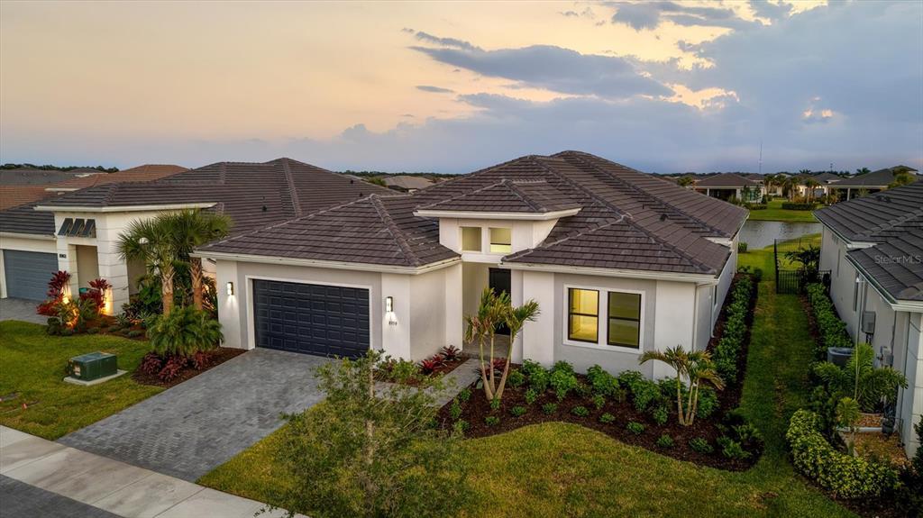 The exterior of a modern house features a dark double door, garage, and palm trees — 8959 BAROQUE TERRACE, SARASOTA, FL