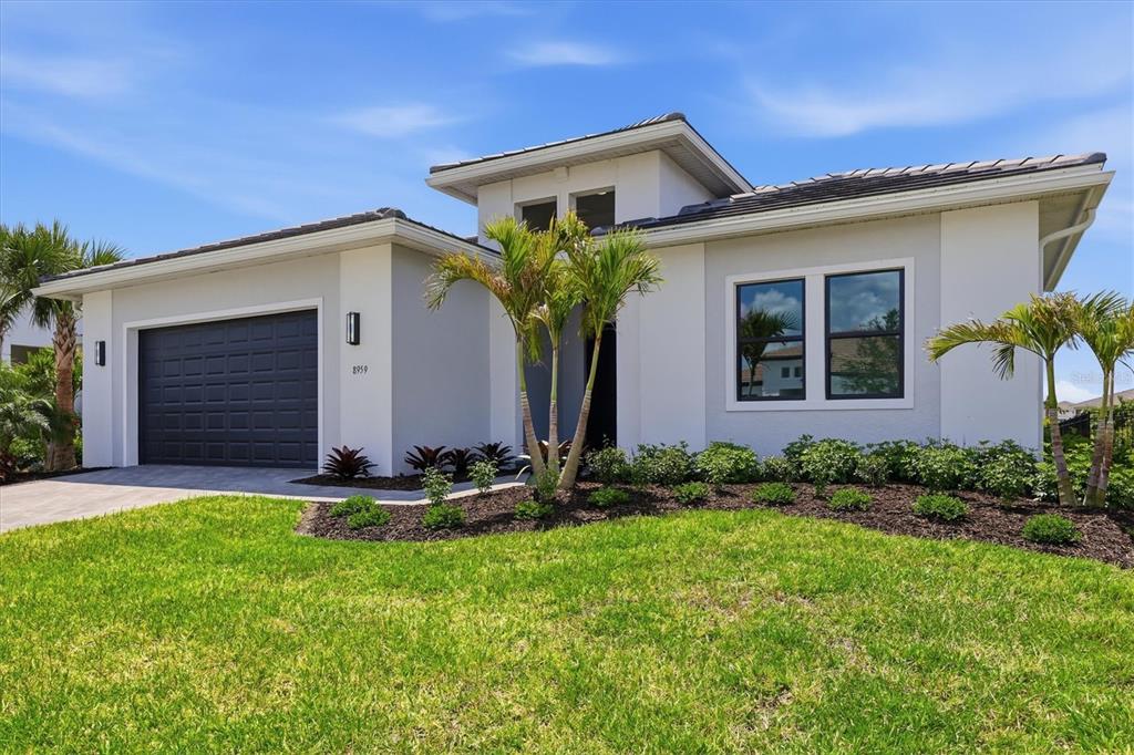 A single-story suburban house with a dark tiled roof, gray exterior, and paved driveway — 8959 BAROQUE TERRACE, SARASOTA, FL