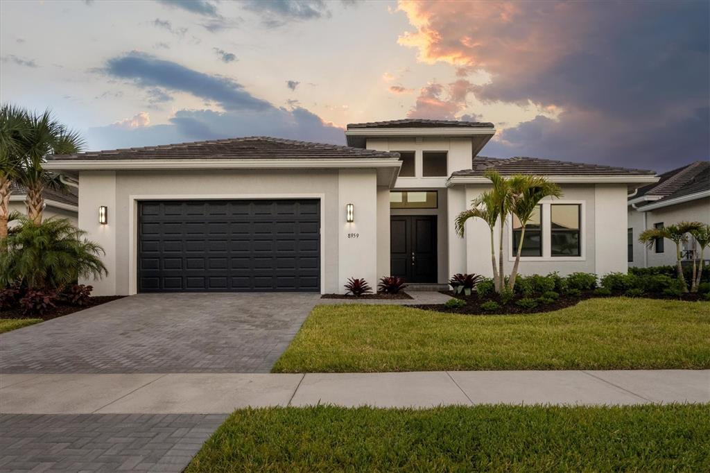 A grassy lawn with palm trees overlooks a pond and houses in the distance — 8959 BAROQUE TERRACE, SARASOTA, FL