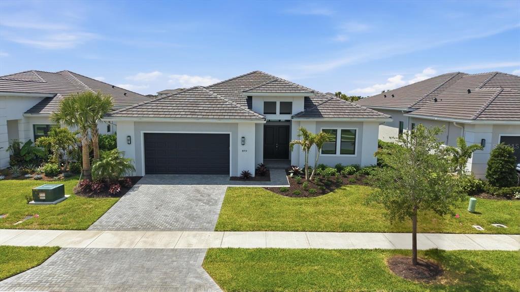 A modern single-story house with a gray garage, white stucco exterior, and palm trees — 8959 BAROQUE TERRACE, SARASOTA, FL