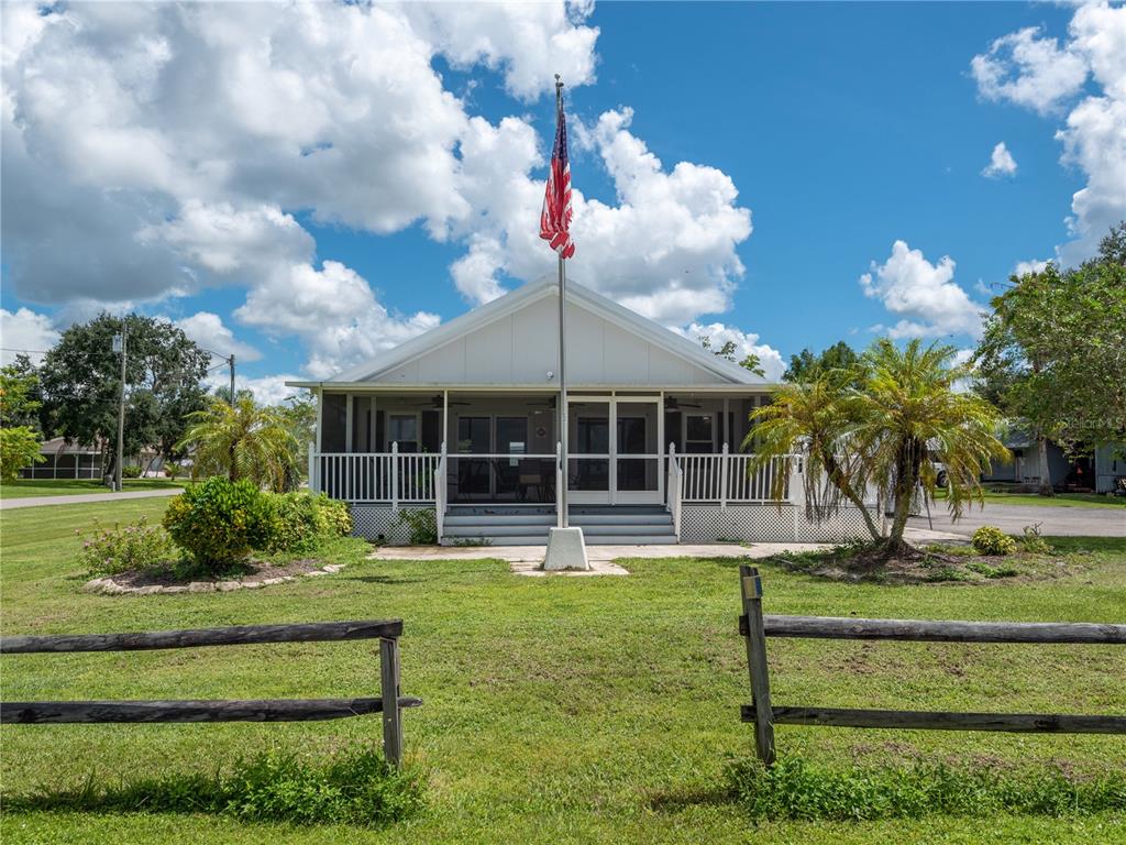 A single-story house with a screened porch and a flagpole stands behind a wooden fence — 38 GRAPE AVENUE, PUNTA GORDA, FL
