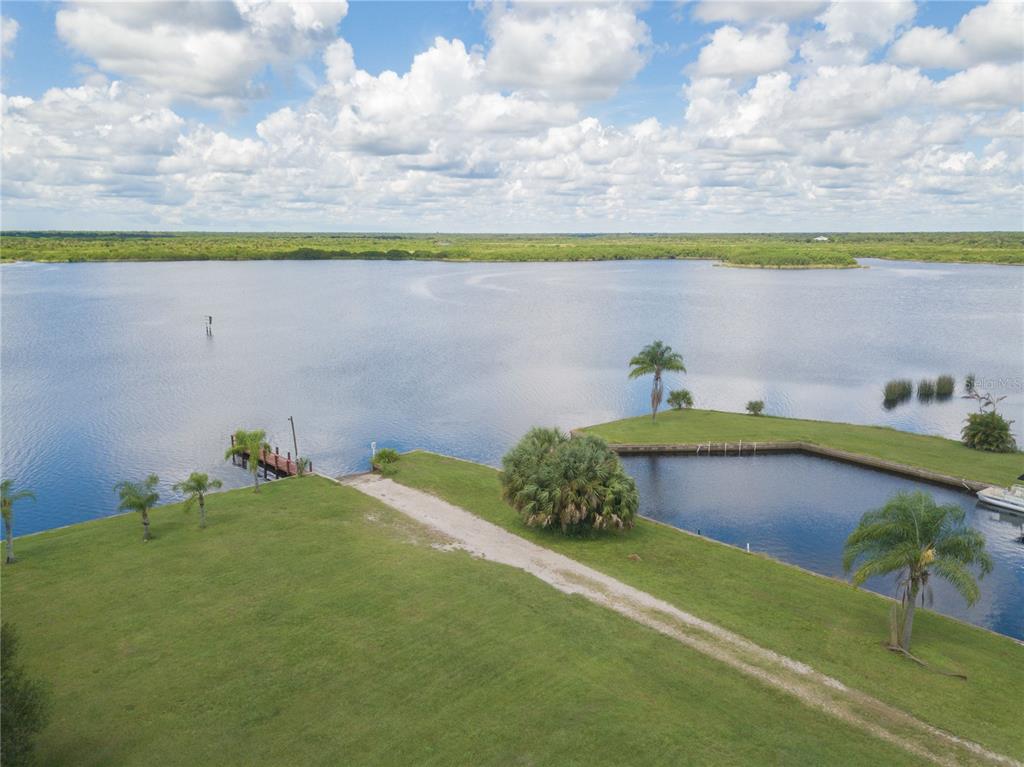 An aerial view shows a grassy lawn, a boat dock, and a canal leading to a lake — 38 GRAPE AVENUE, PUNTA GORDA, FL