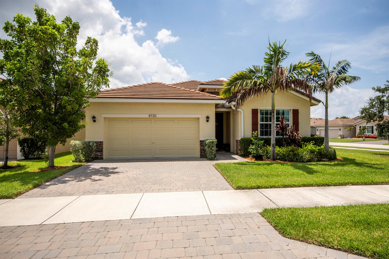 A single-story house with a tan stucco exterior, tile roof, and a paved driveway — 4720 NW Exchange Avenue, Jensen Beach FL 34957, JENSEN BEACH, FL