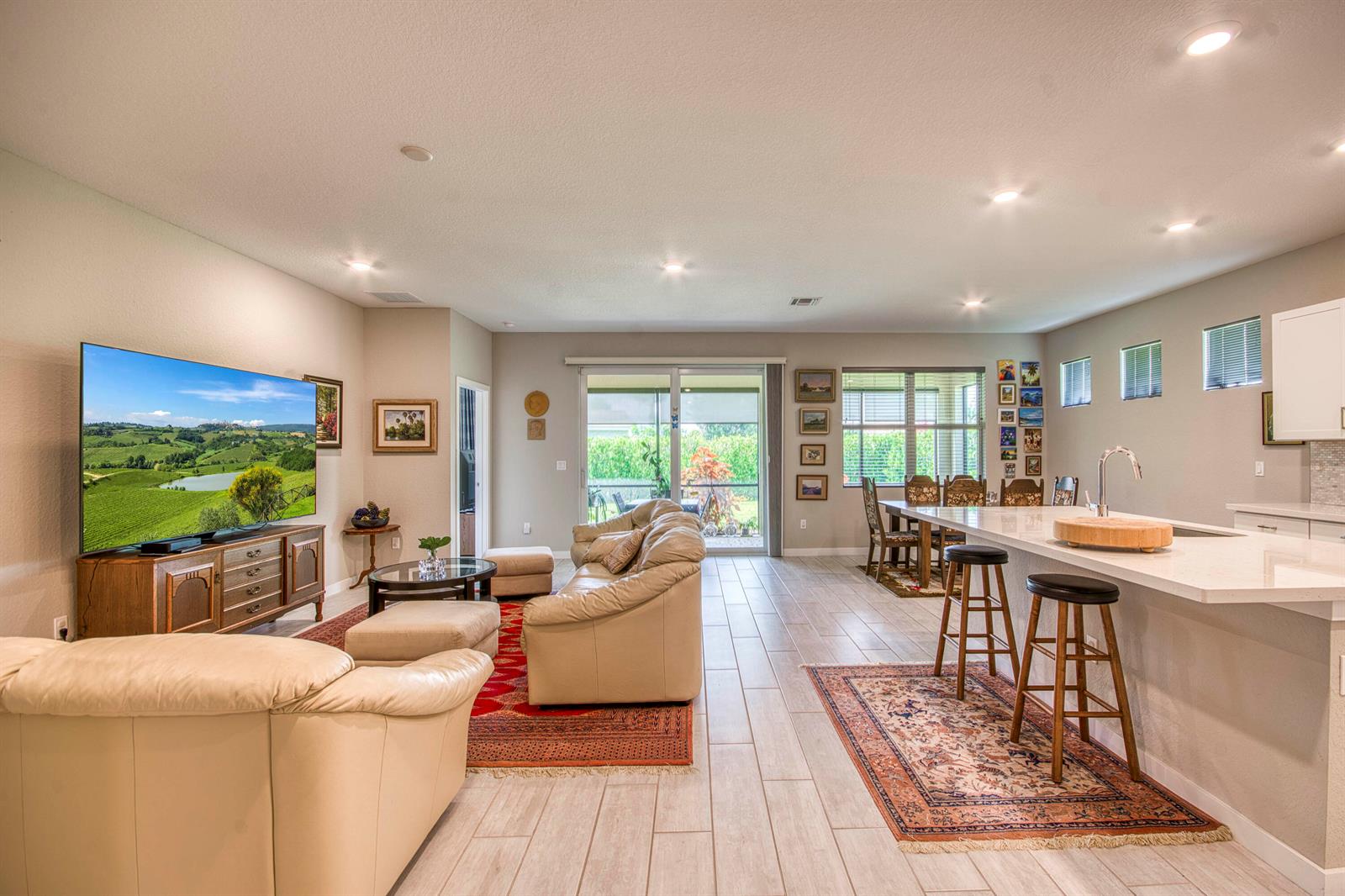 An open-concept living room and kitchen featuring tile floors, leather furniture, and a large island — 4720 NW Exchange Avenue, Jensen Beach FL 34957, JENSEN BEACH, FL