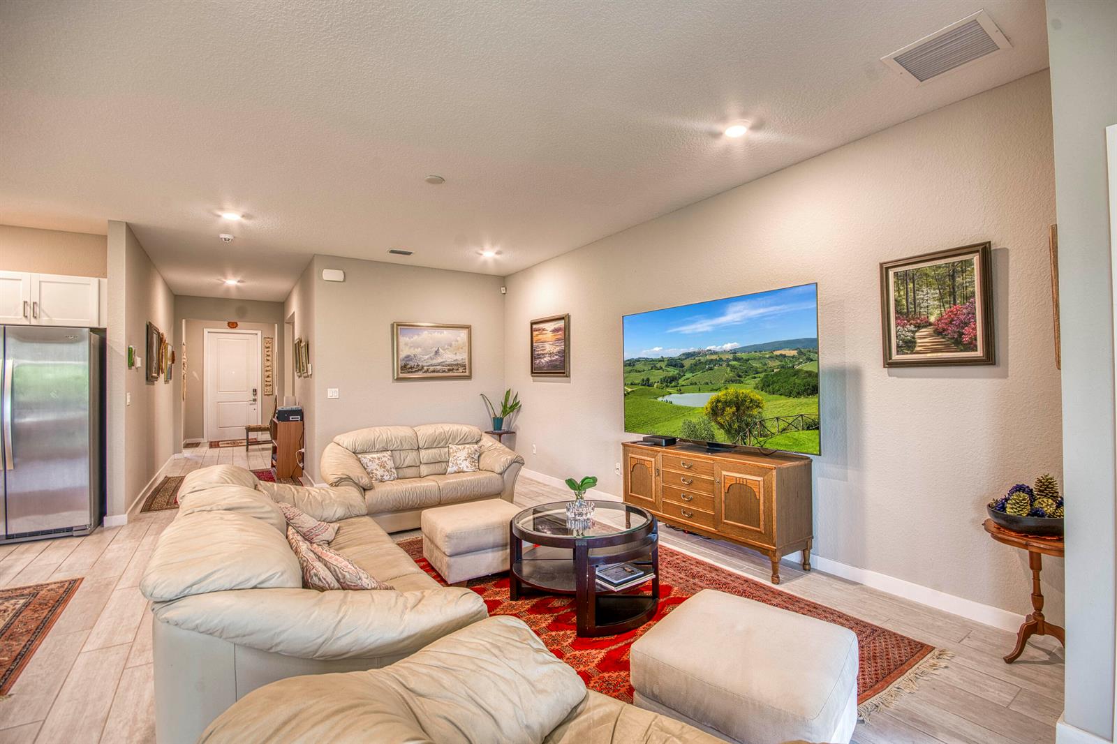 A living room features light-colored leather sofas, a wooden media console, and a red area rug — 4720 NW Exchange Avenue, Jensen Beach FL 34957, JENSEN BEACH, FL