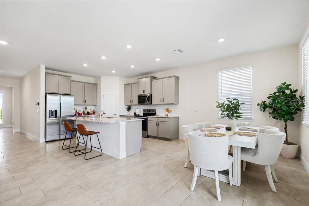 A modern kitchen with gray cabinets, stainless steel appliances, and an adjacent dining area — 5689 HAWKS CAY STREET, APOLLO BEACH, FL