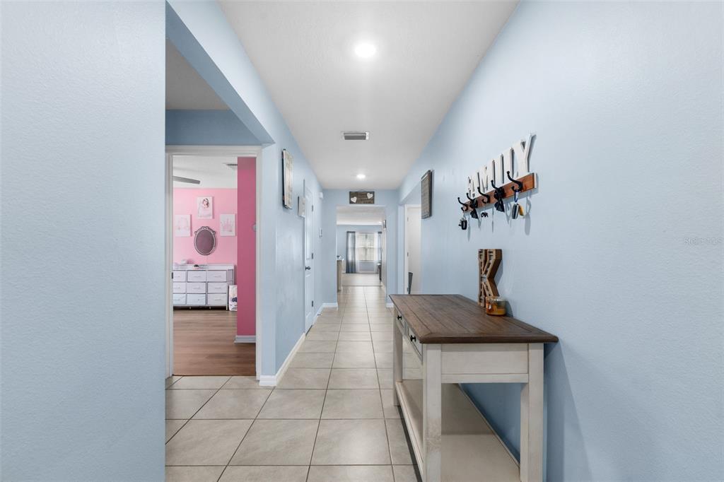 A hallway with light blue walls, tile flooring, and a wooden console table — 16467 NW 192ND TERRACE, HIGH SPRINGS, FL