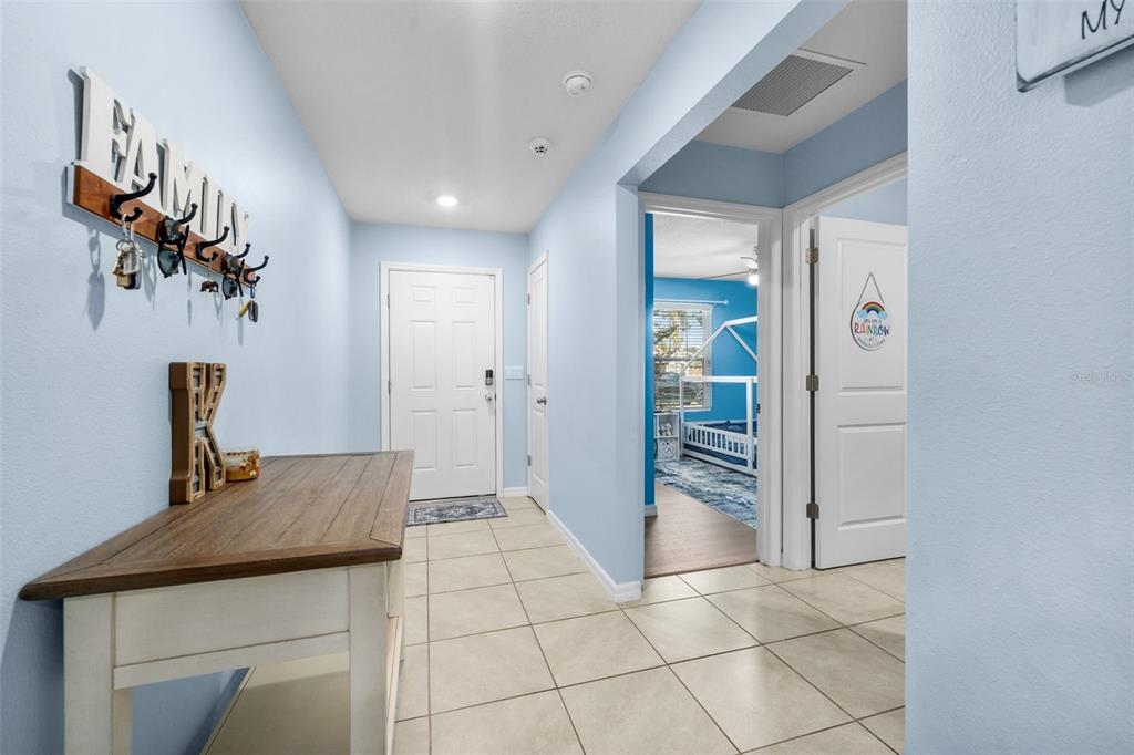 A light blue entryway features a wooden console table, a coat rack, and tiled flooring — 16467 NW 192ND TERRACE, HIGH SPRINGS, FL
