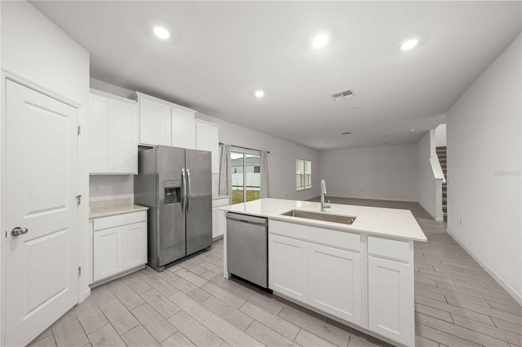A modern kitchen features white cabinets, stainless steel appliances, a center island, and tile flooring — 3980 NE 34TH AVENUE, OCALA, FL