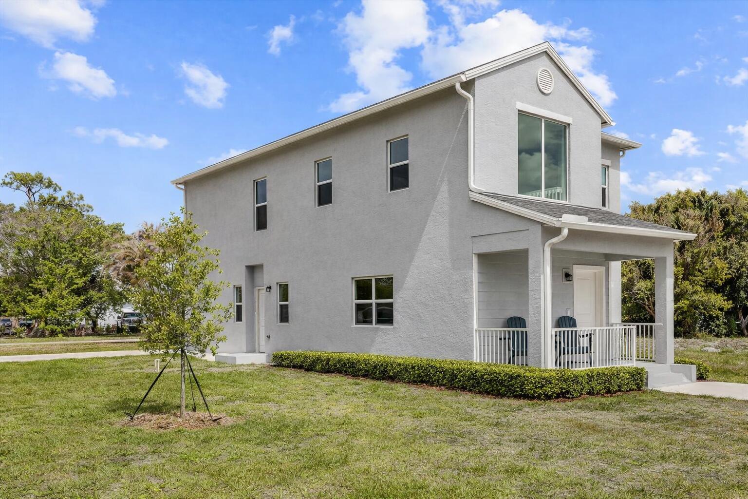 A two-story gray stucco house features a front porch and a small landscaped hedge — 2585 SE Bonita Street, Stuart FL 34997, STUART, FL