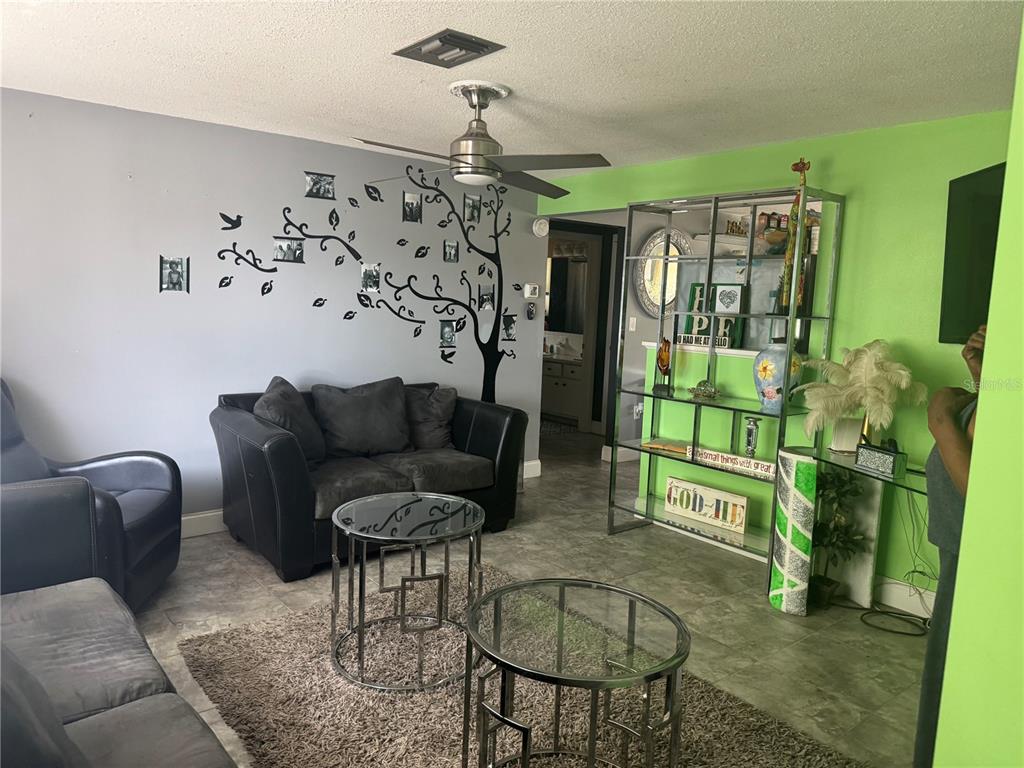 A living room features gray and lime green walls, a tree wall decal, and glass furniture — 10424 CHOICE DRIVE, PORT RICHEY, FL