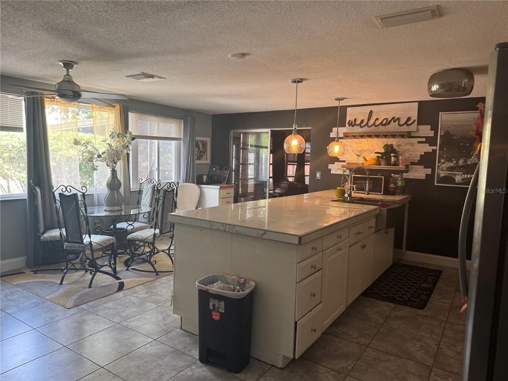 A kitchen features a large white island, pendant lighting, and an adjacent dining area — 10424 CHOICE DRIVE, PORT RICHEY, FL