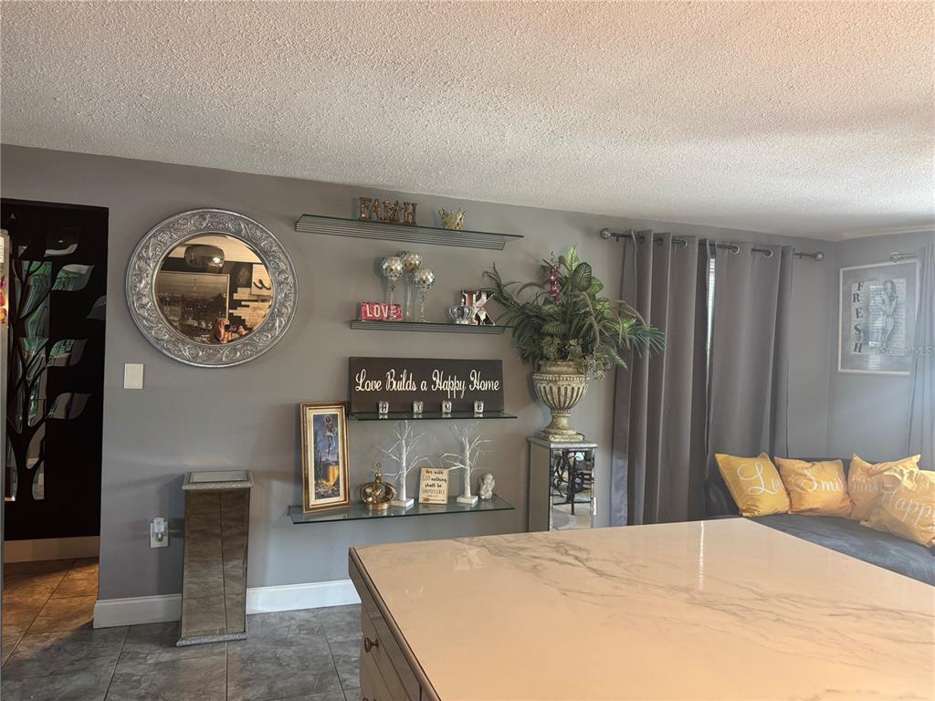 A living room features gray walls, a circular mirror, glass shelving, and a marble-topped island — 10424 CHOICE DRIVE, PORT RICHEY, FL