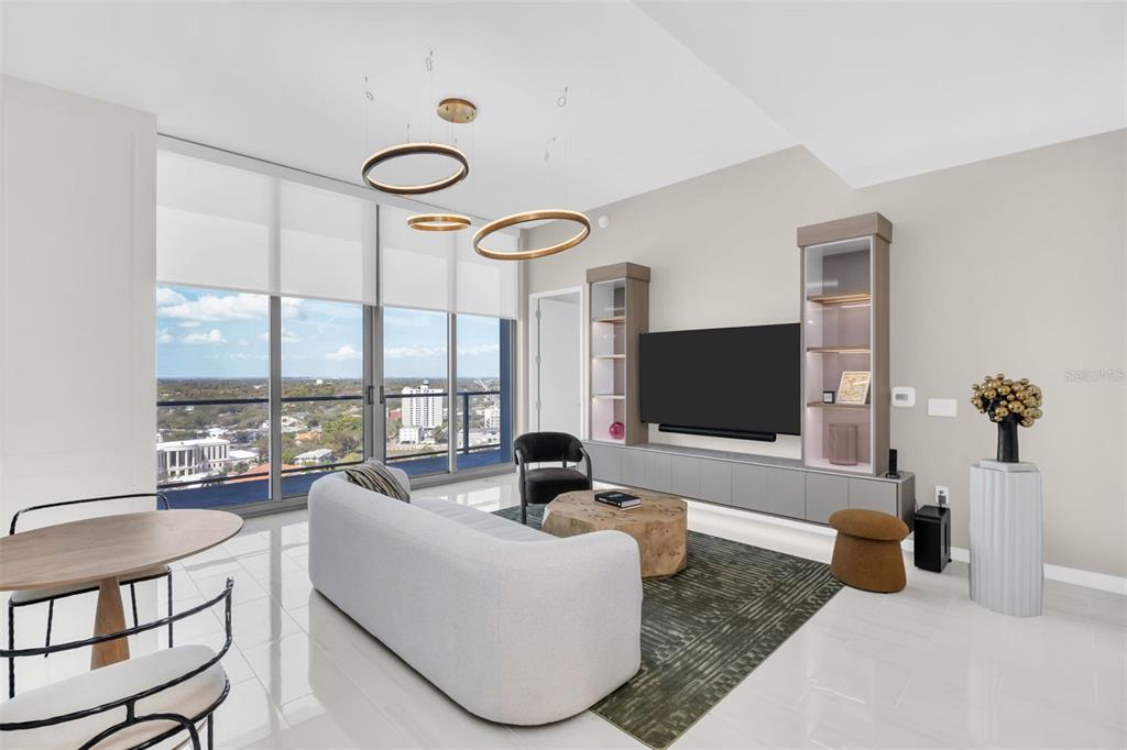 A modern living room features a white sofa, a television unit, and floor-to-ceiling windows — 400 CENTRAL AVENUE UNIT 2705, ST PETERSBURG, FL