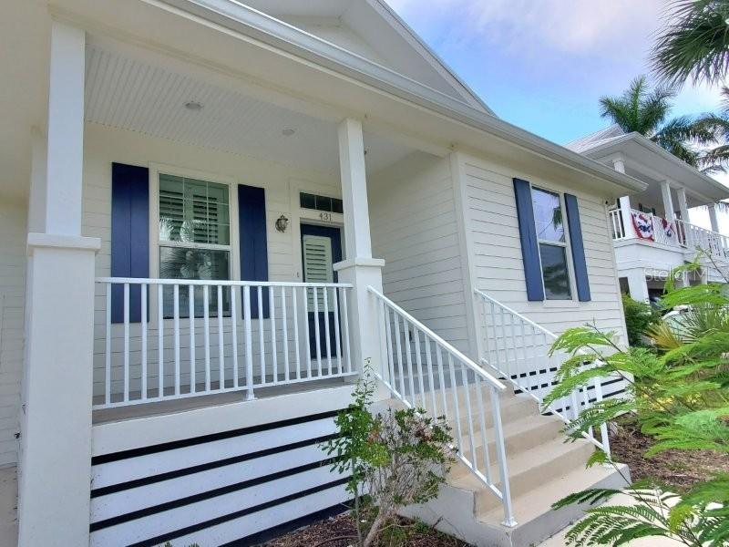 A white house exterior features a front porch with blue shutters and white railings — 431 W MCKENZIE STREET, PUNTA GORDA, FL