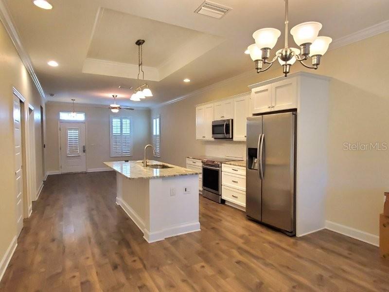 A kitchen features white cabinets, stainless steel appliances, a center island, and wood-look flooring — 431 W MCKENZIE STREET, PUNTA GORDA, FL