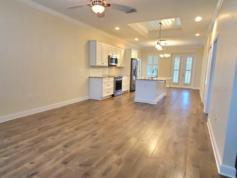 An open-concept kitchen features white cabinetry, stainless steel appliances, and light wood flooring — 431 W MCKENZIE STREET, PUNTA GORDA, FL