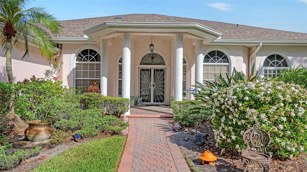 A front exterior view of a house with a brick walkway and white columns — 7025 N SERENOA DRIVE, SARASOTA, FL