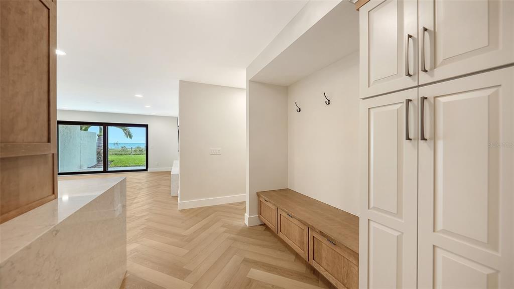 A mudroom area features a built-in bench and cabinets, leading to a room with ocean views — 2089 GULF OF MEXICO DRIVE UNIT G1-104, LONGBOAT KEY, FL