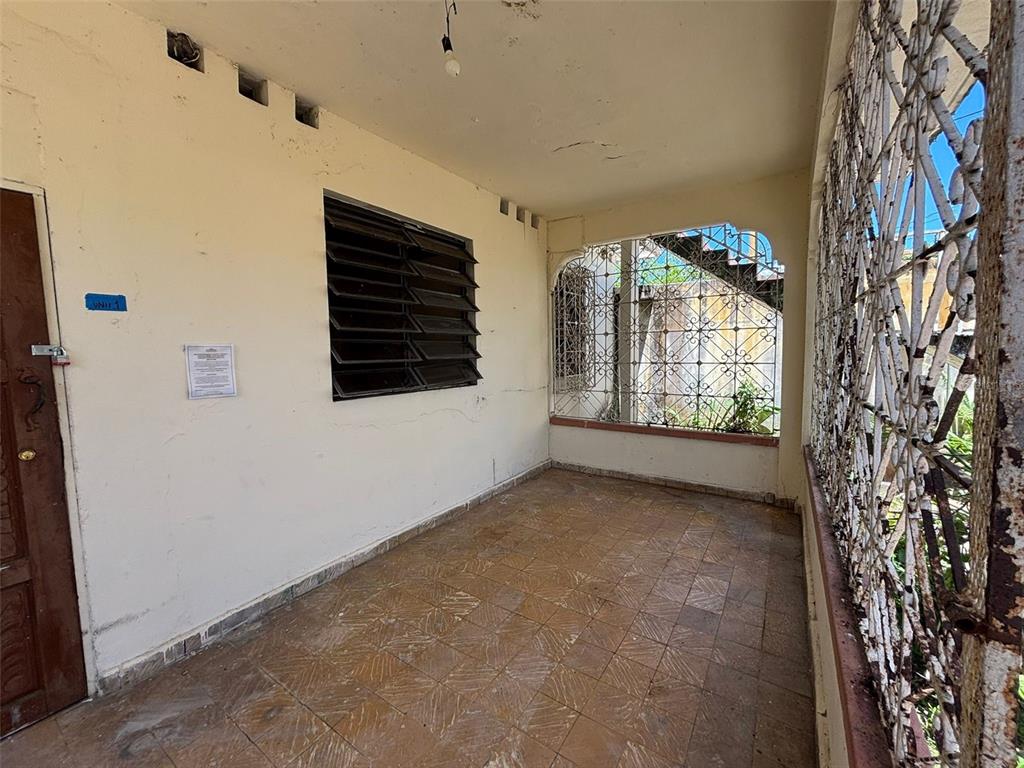 A covered porch with tiled flooring, a louvered window, and decorative metal security grilles — D-13C Fajardo St. MIRAPALMERAS, SAN JUAN, PR