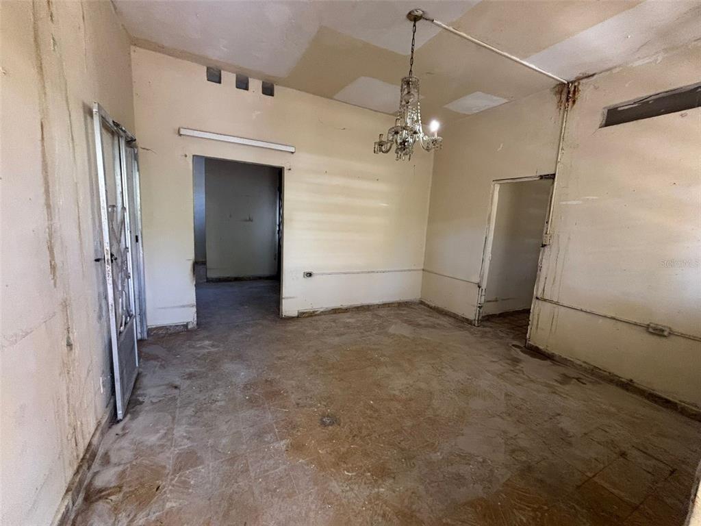 An interior view of a room with bare walls, tile flooring, and a hanging chandelier — D-13C Fajardo St. MIRAPALMERAS, SAN JUAN, PR