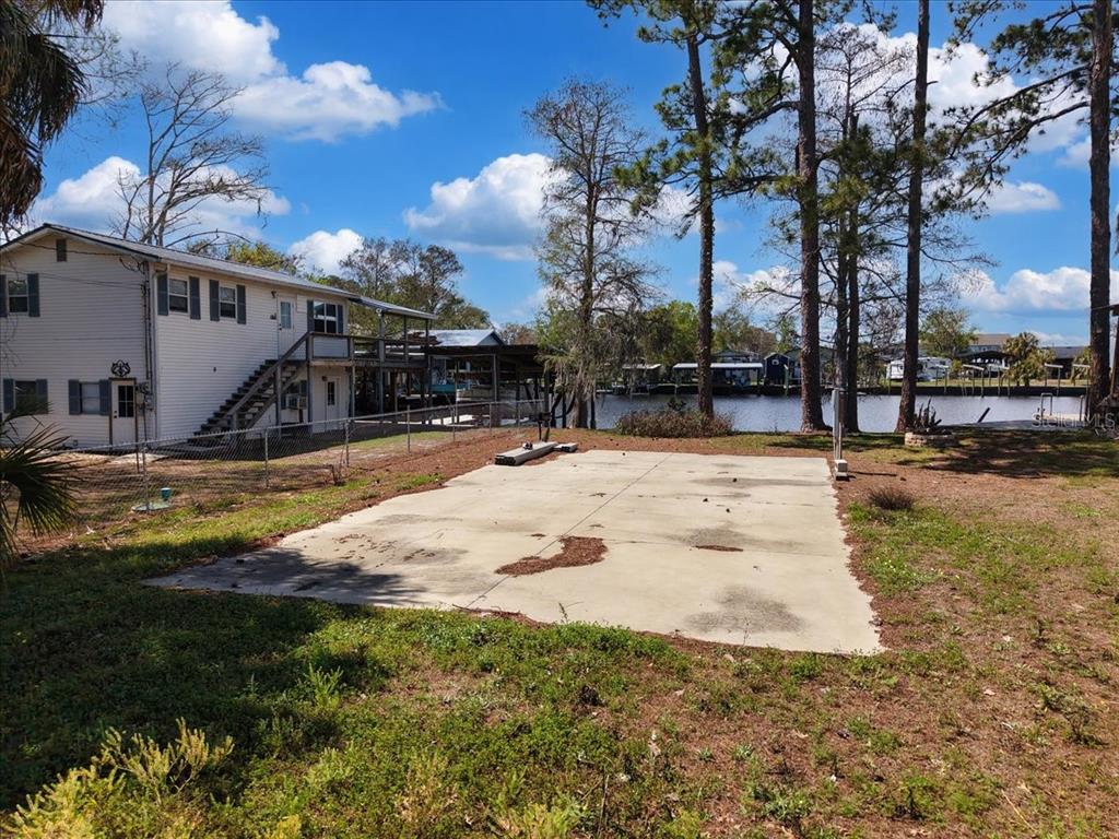 A concrete slab sits in a grassy backyard next to a two-story house near water — 000 SE SE 241 STREET, OLD TOWN, FL