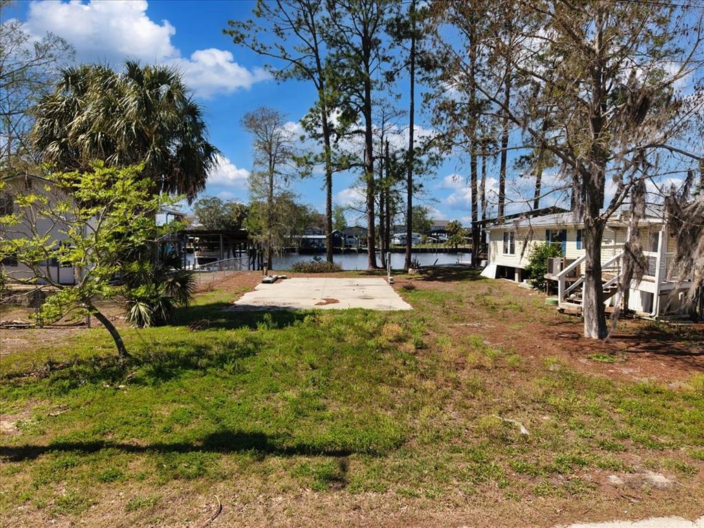 A vacant lot with a concrete slab sits between two houses near a waterfront canal — 000 SE SE 241 STREET, OLD TOWN, FL