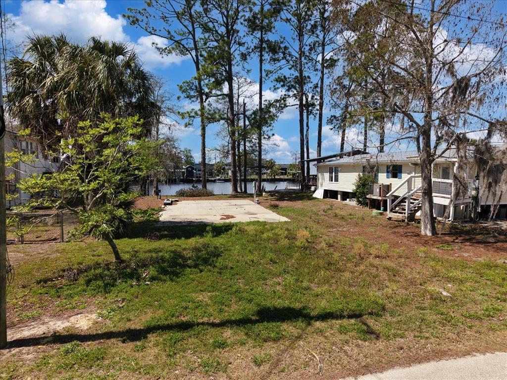 A vacant lot with a concrete slab sits between two houses near a body of water — 000 SE SE 241 STREET, OLD TOWN, FL