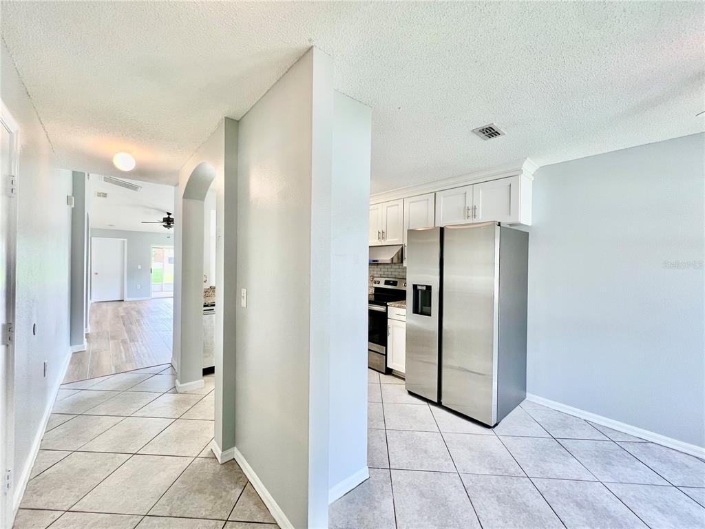 A view from a tiled kitchen area looking through an arched doorway toward a living space — 27147 BIG SUR DRIVE, WESLEY CHAPEL, FL