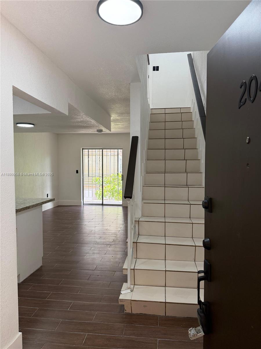 An entryway leads to a tiled staircase and a living area with wood-look flooring — 6625 W 4th Ave # 204, Hialeah FL 33012, HIALEAH, FL