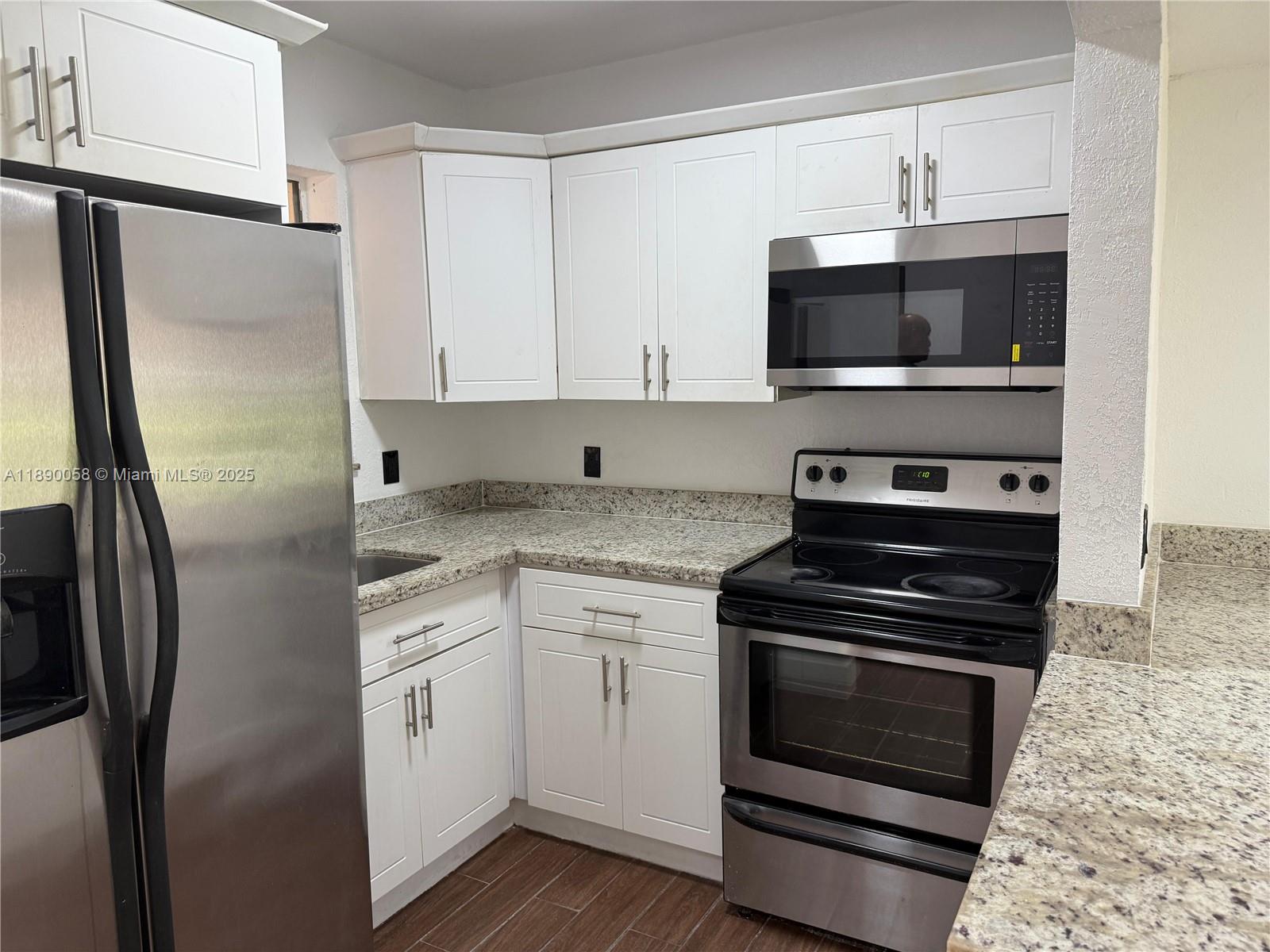 A kitchen features white cabinets, stainless steel appliances, and speckled granite countertops — 6625 W 4th Ave # 204, Hialeah FL 33012, HIALEAH, FL