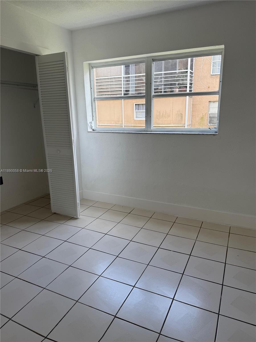 A bedroom features white walls, light-colored floor tiles, a closet, and a window — 6625 W 4th Ave # 204, Hialeah FL 33012, HIALEAH, FL
