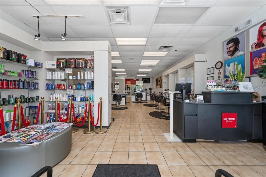 The interior of a hair salon features tiled floors, product display shelves, and a reception desk — 13880 LANDSTAR BOULEVARD, ORLANDO, FL