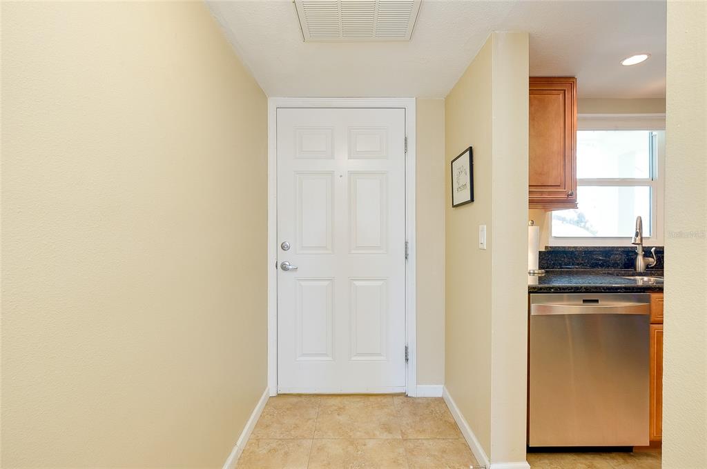 A tiled entryway leads to a white front door next to a kitchen with stainless appliances — 104 CAPRI ISLES BOULEVARD UNIT 209, VENICE, FL