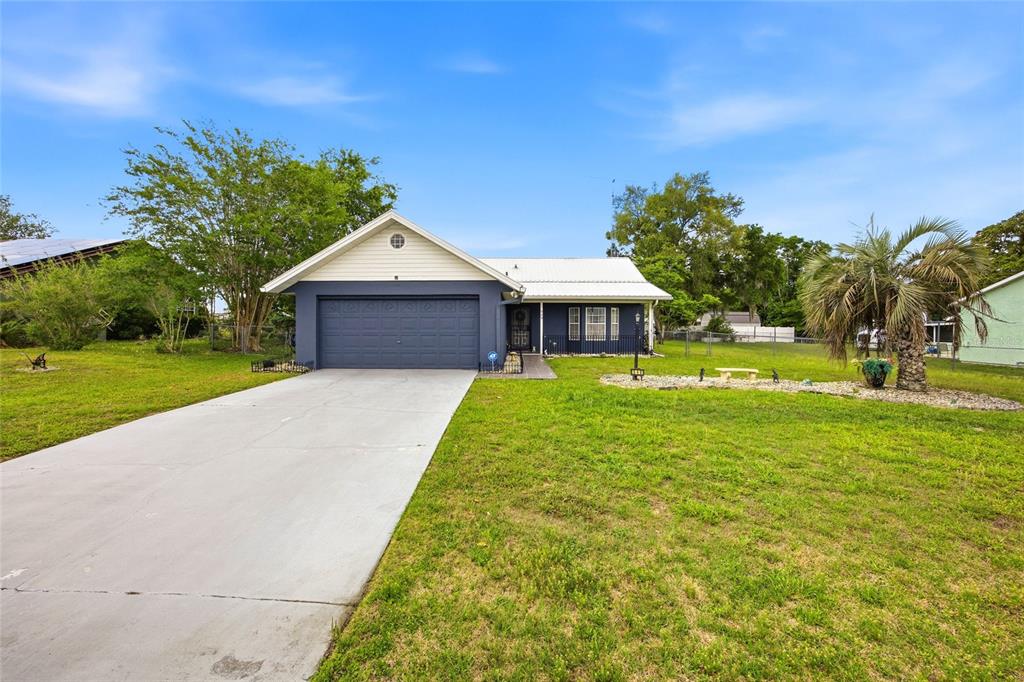 A single-story house with a blue exterior, white roof, and a concrete driveway — 549 SILVER COURSE RUN, OCALA, FL