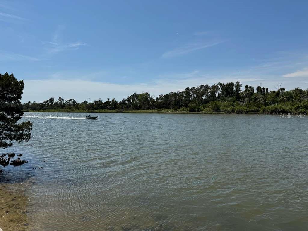 A small motorboat travels across a wide river with a treelined shore in the background — 11624 N LANDOVER TERRACE, DUNNELLON, FL