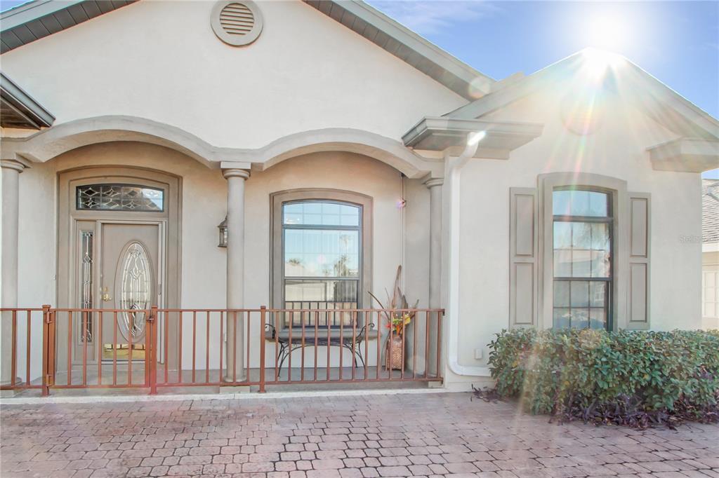 The exterior of a house features a paved driveway, a gated porch, and arched windows — 17996 SE 115TH CIRCLE, SUMMERFIELD, FL
